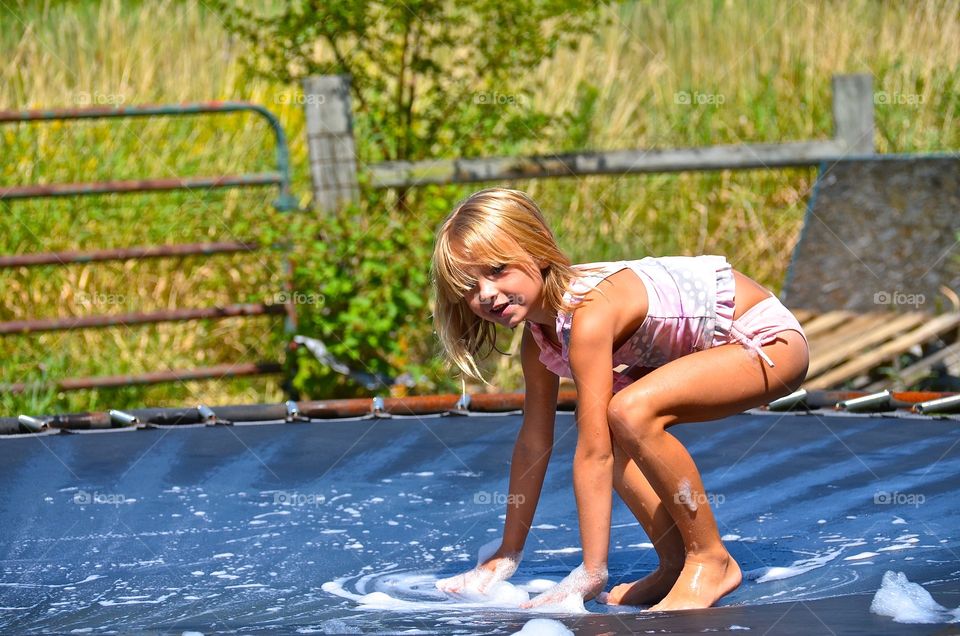 Young blonde girl cleaning trampoline