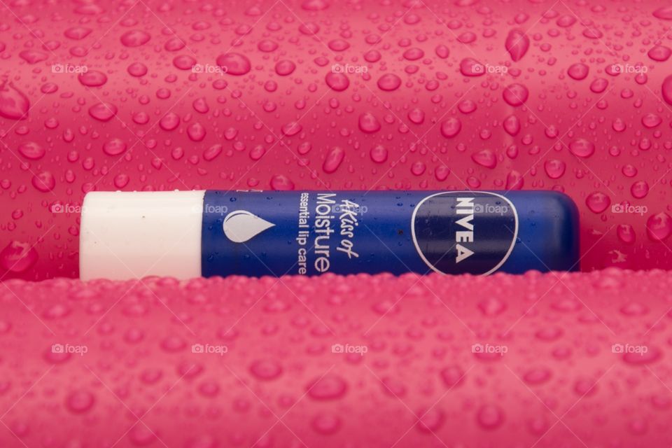 Nivea lip balm laying on a air bed surrounded by raindrops