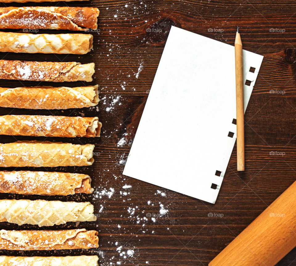 Still life in a rustic style with pastries.  White marshmallow with red currant berries, tea cups and a glass jug of water on a wooden board and textured white napkin.  Tasty snack
