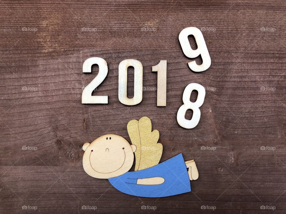 Happy new year 2019, bye 2018, conceptual composition with wooden numbers over wooden floor and a wooden angel