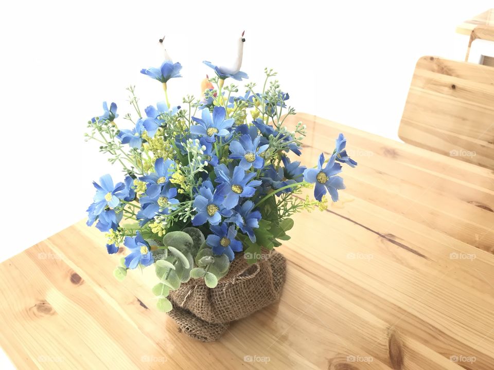 Blue artificial flower in a sack on wooden table