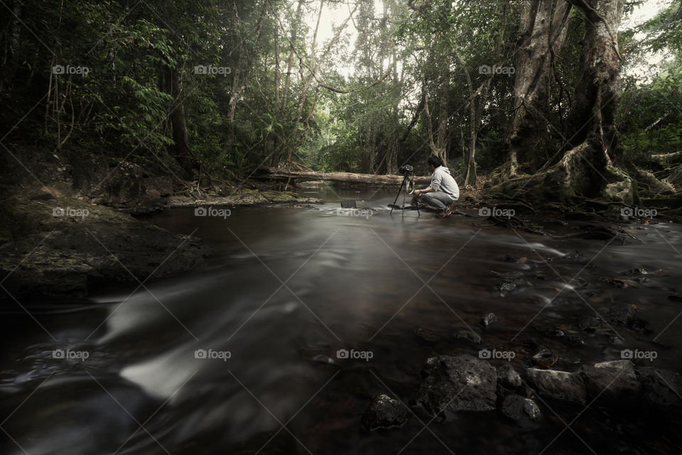 Professional photographer taking a photo in the forest pond