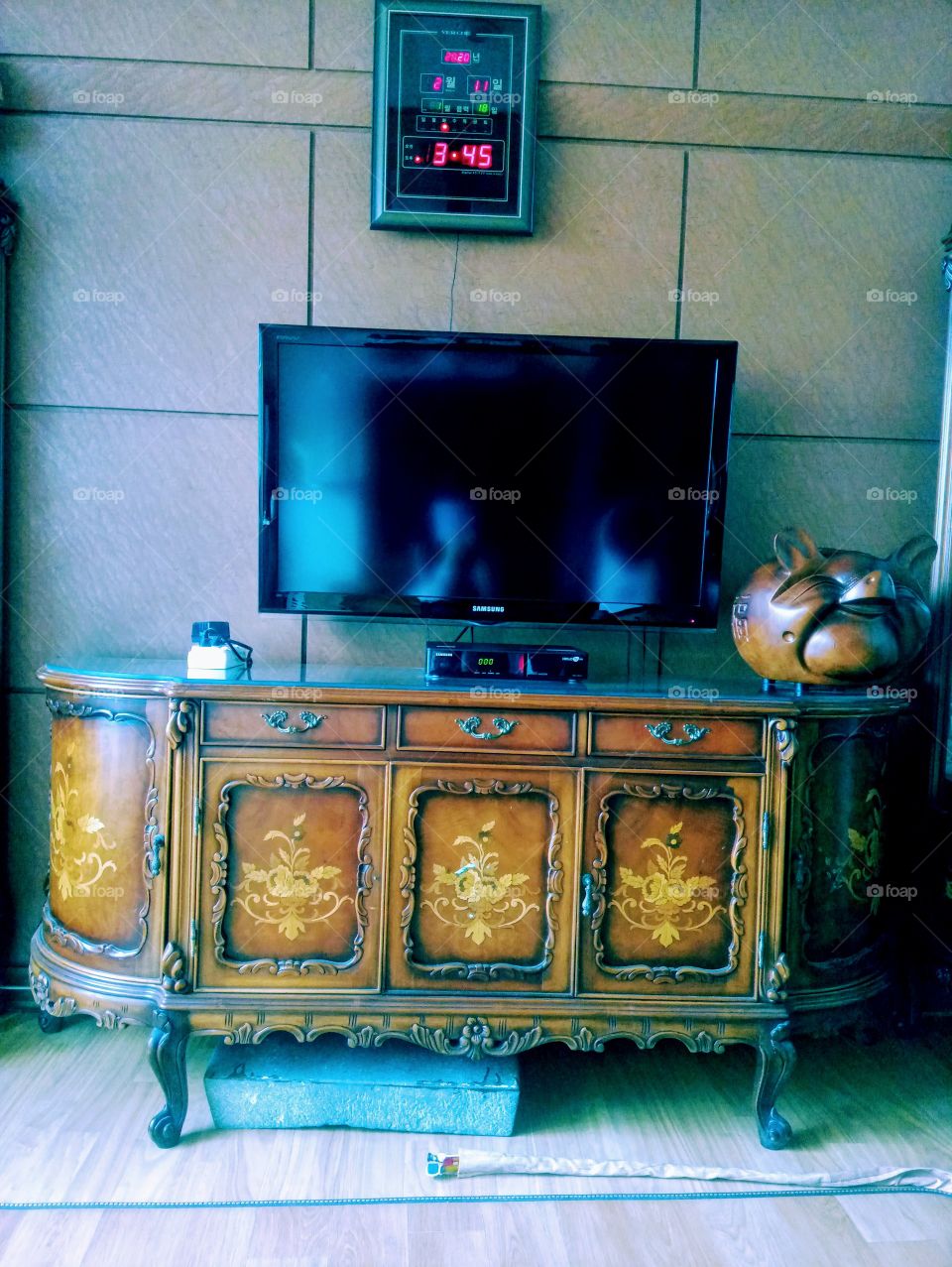 The shapes and line in our living room where you can see the rectangular shape of stone under the cabinet.
the cabinet have shapes of rectagular door.
square tv, rectangular hanging clock, big piggy bank and the lines and shapes on the wall.