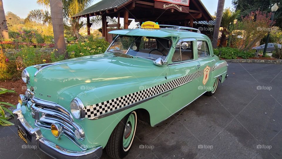 Vintage green checkered taxicab waiting in front of a restaurant 