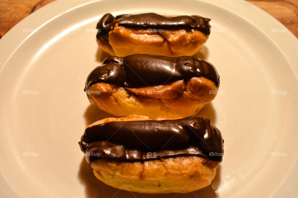 Three Chocolate Eclair Pastries Served On A White Plate