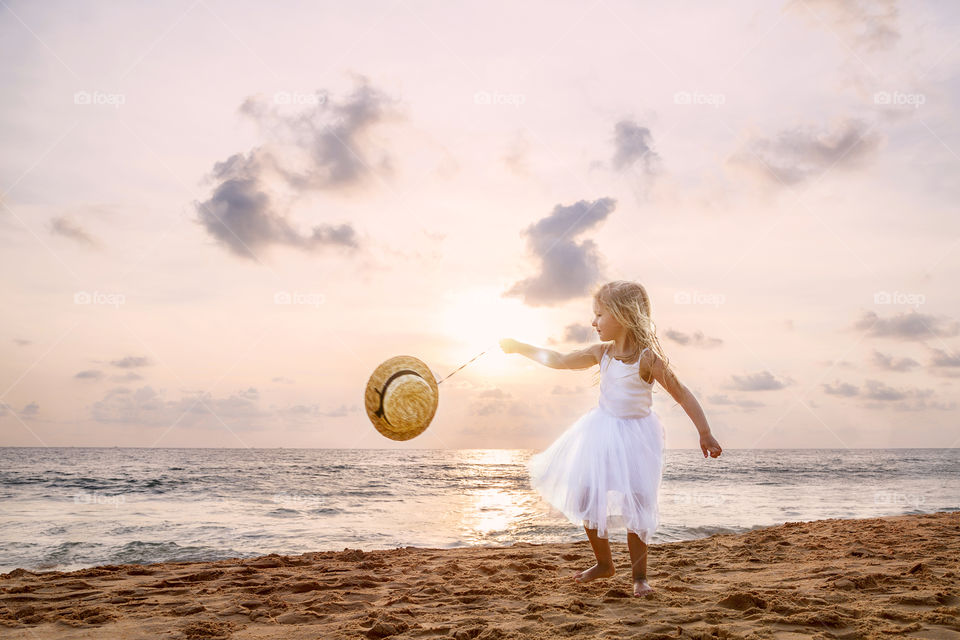Beautiful little girl playing on the sandy beach on sunset 
