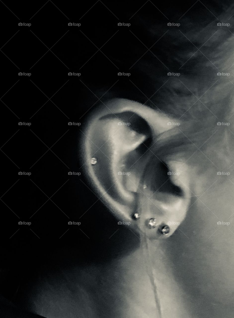A girls ear piercing multiple times on one ear including the cartilage, wearing little diamond earrings. 