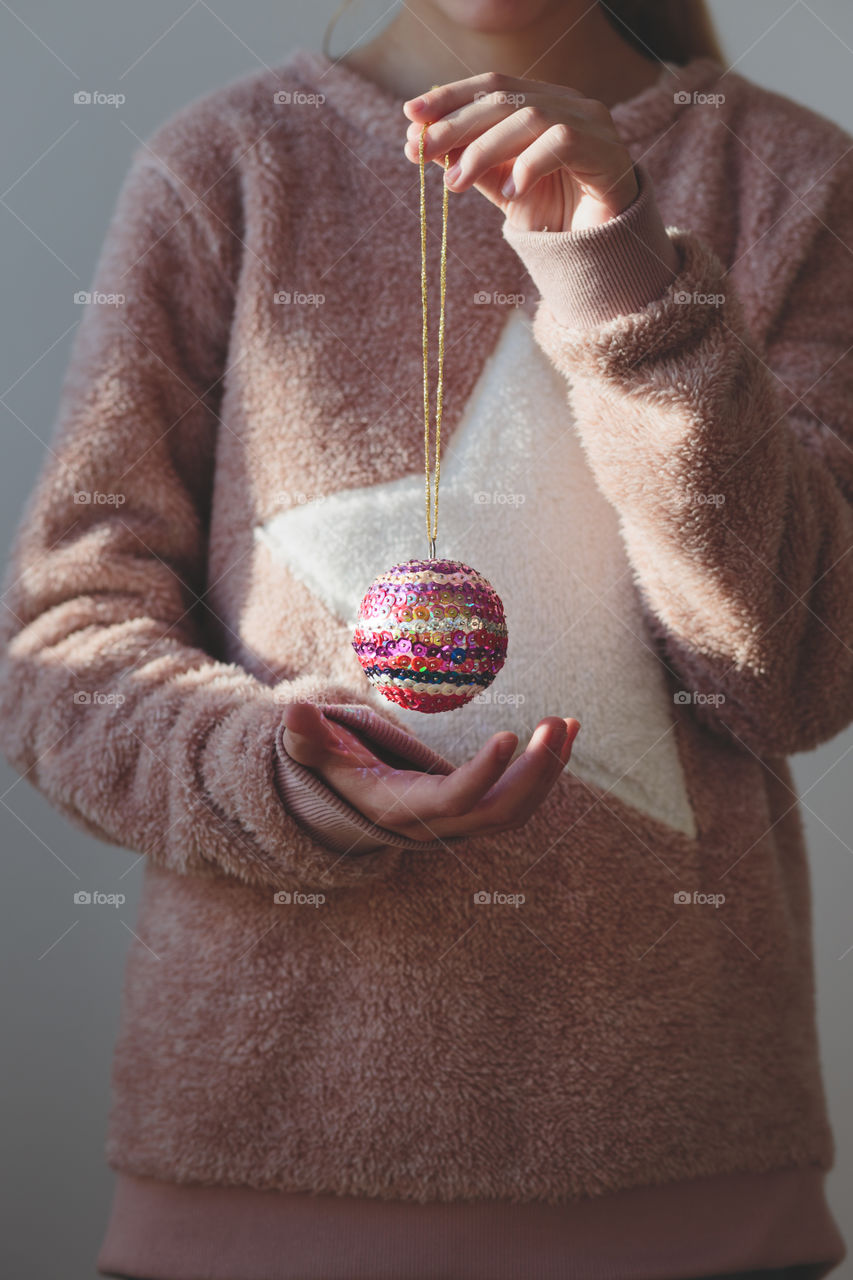Young girl wearing warm sweater and enjoying her handmade colorful Christmas decoration ball