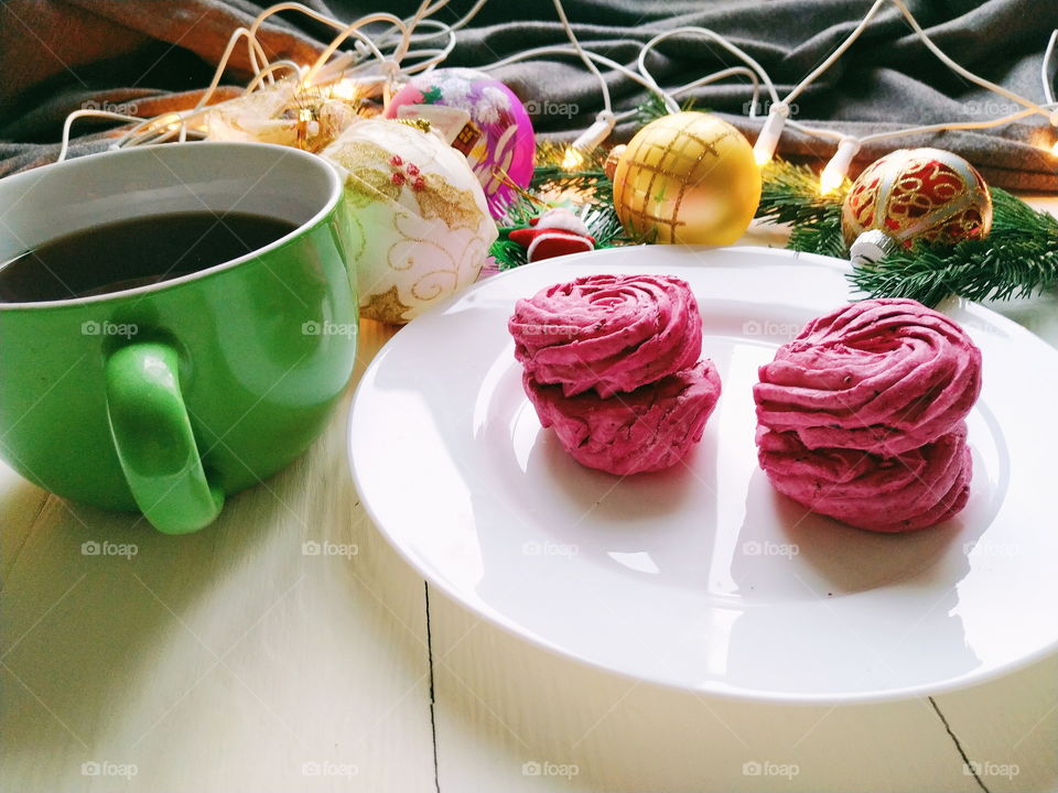 Christmas toys, a cup of hot tea, marshmallows and Christmas decorations on a white table