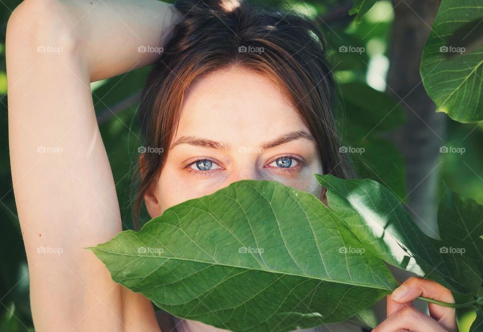 Portrait of girl hiding behind the green leaf