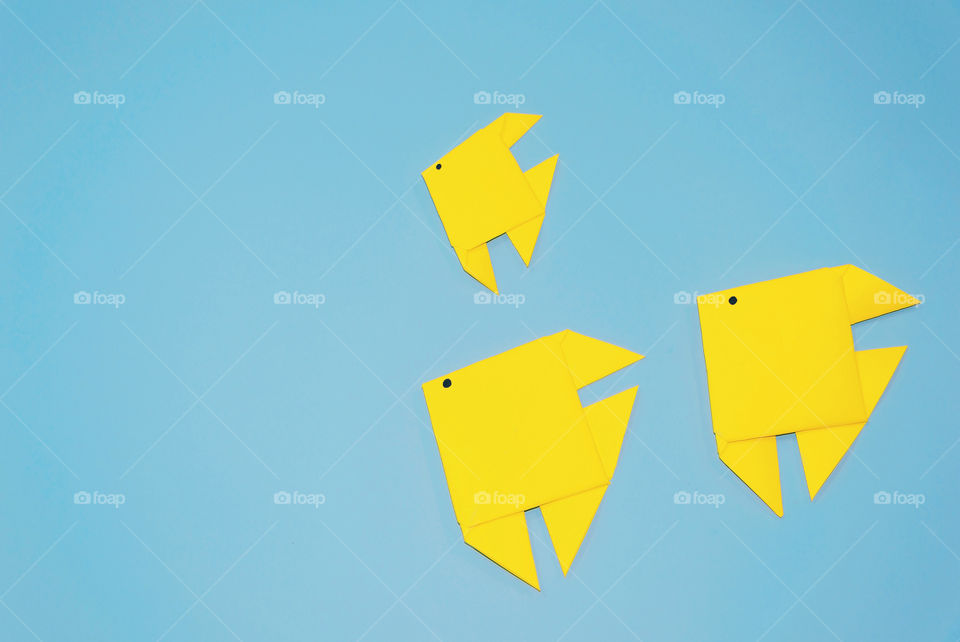 Origami yellow fish on blue background