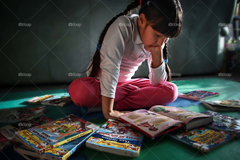 Cute little girl is reading a book