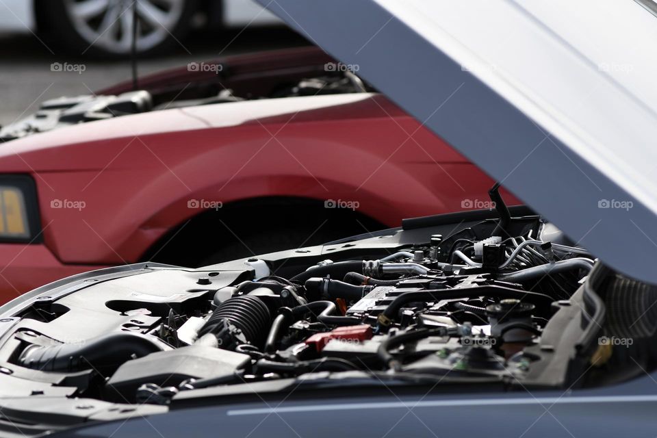 The hood to a Honda Accord is open next to a Ford Mustang as the owner prepares to give a jump start.