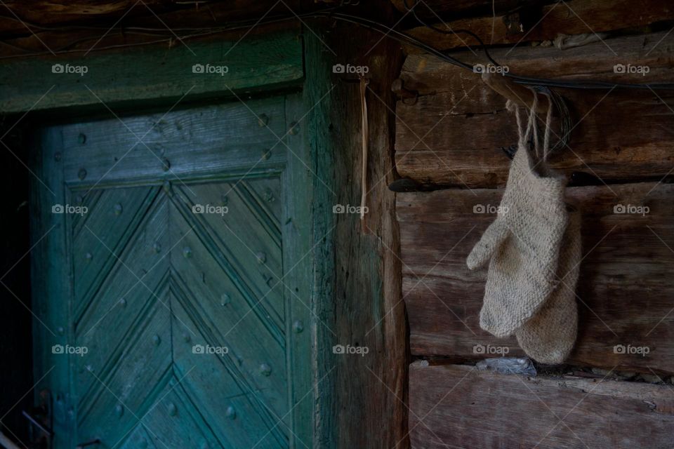 Wooden house with green wooden door and a pair of knitted gloves hanging next to the door 