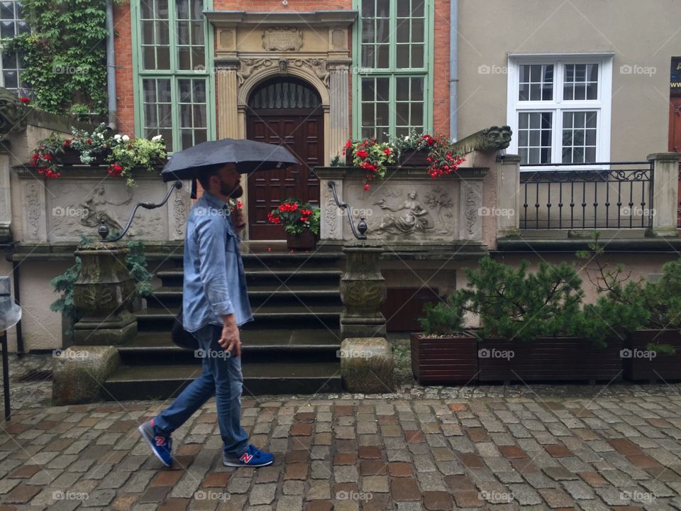 Man walking with umbrella near roadside