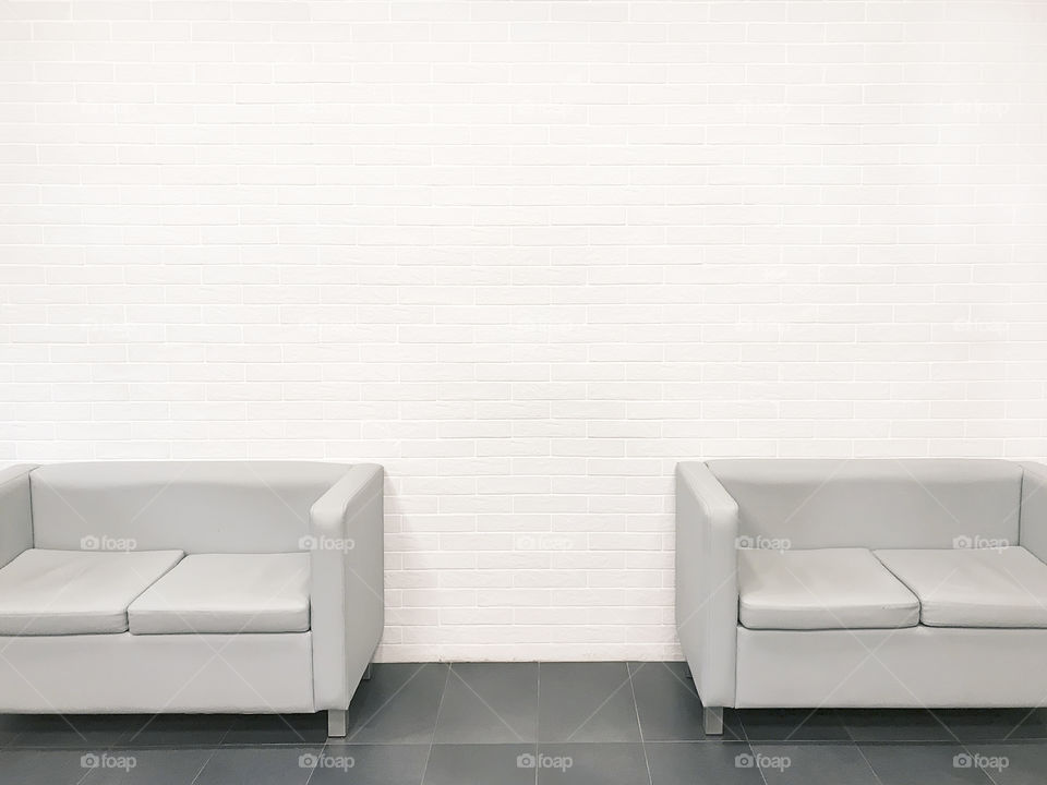 Two grey empty sofas in empty grey room 