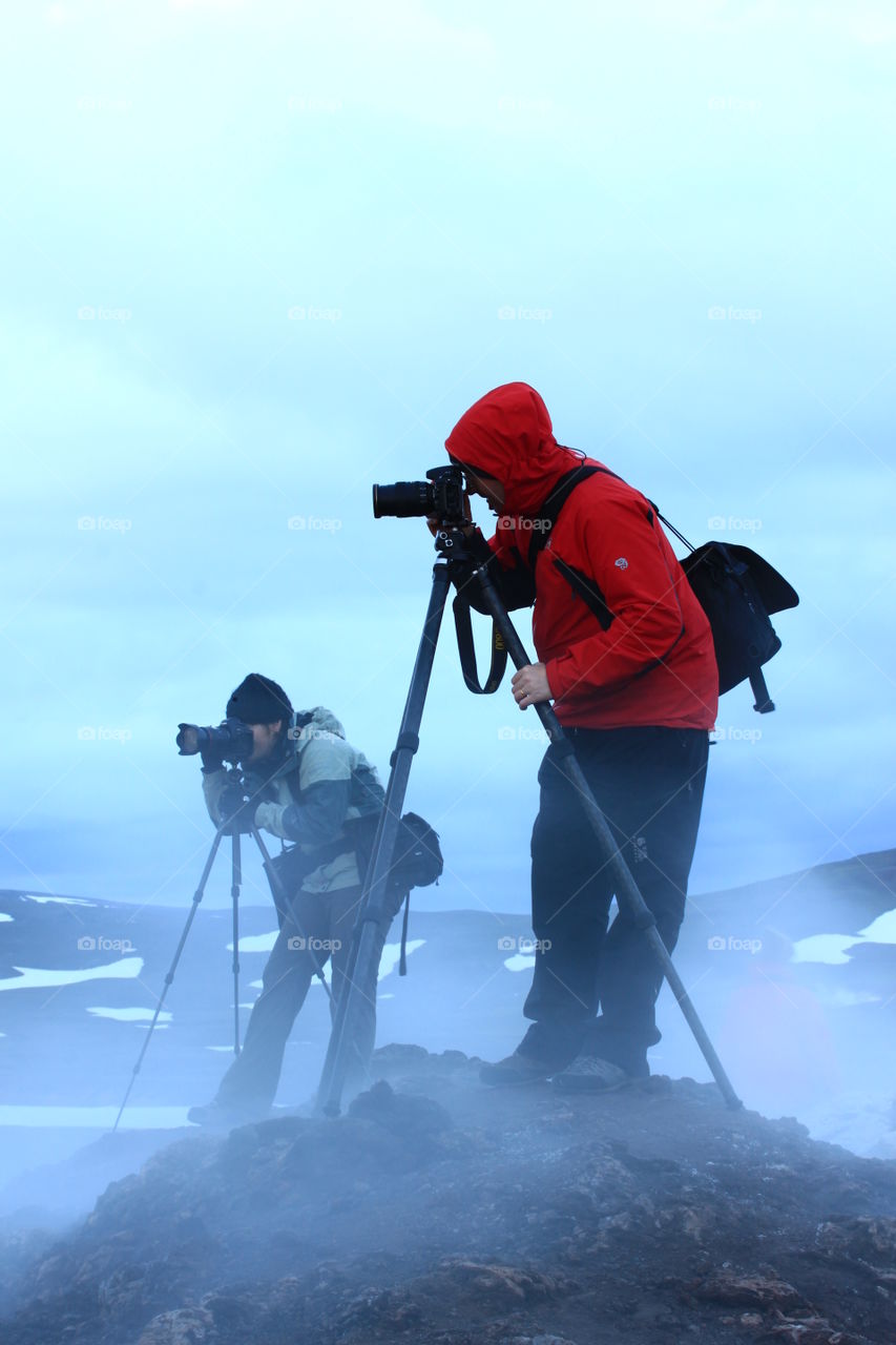 Photographers taking photos in steaming volcanic lava fields in Iceland