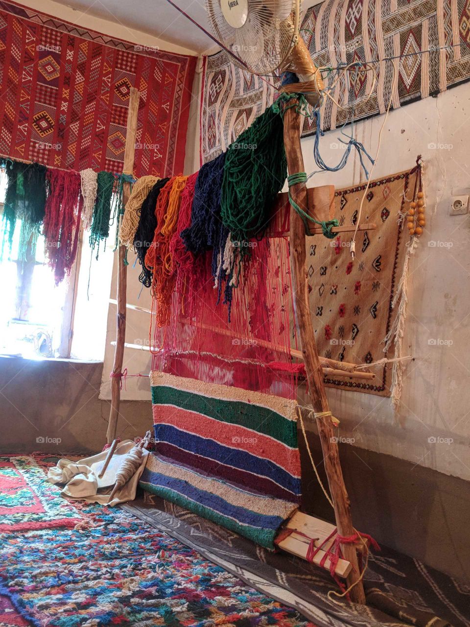 Ornate, Handwoven, Handmade Rug on a Look Surrounded by Wool, Thread, and Rugs in a Tiny Village in Morocco