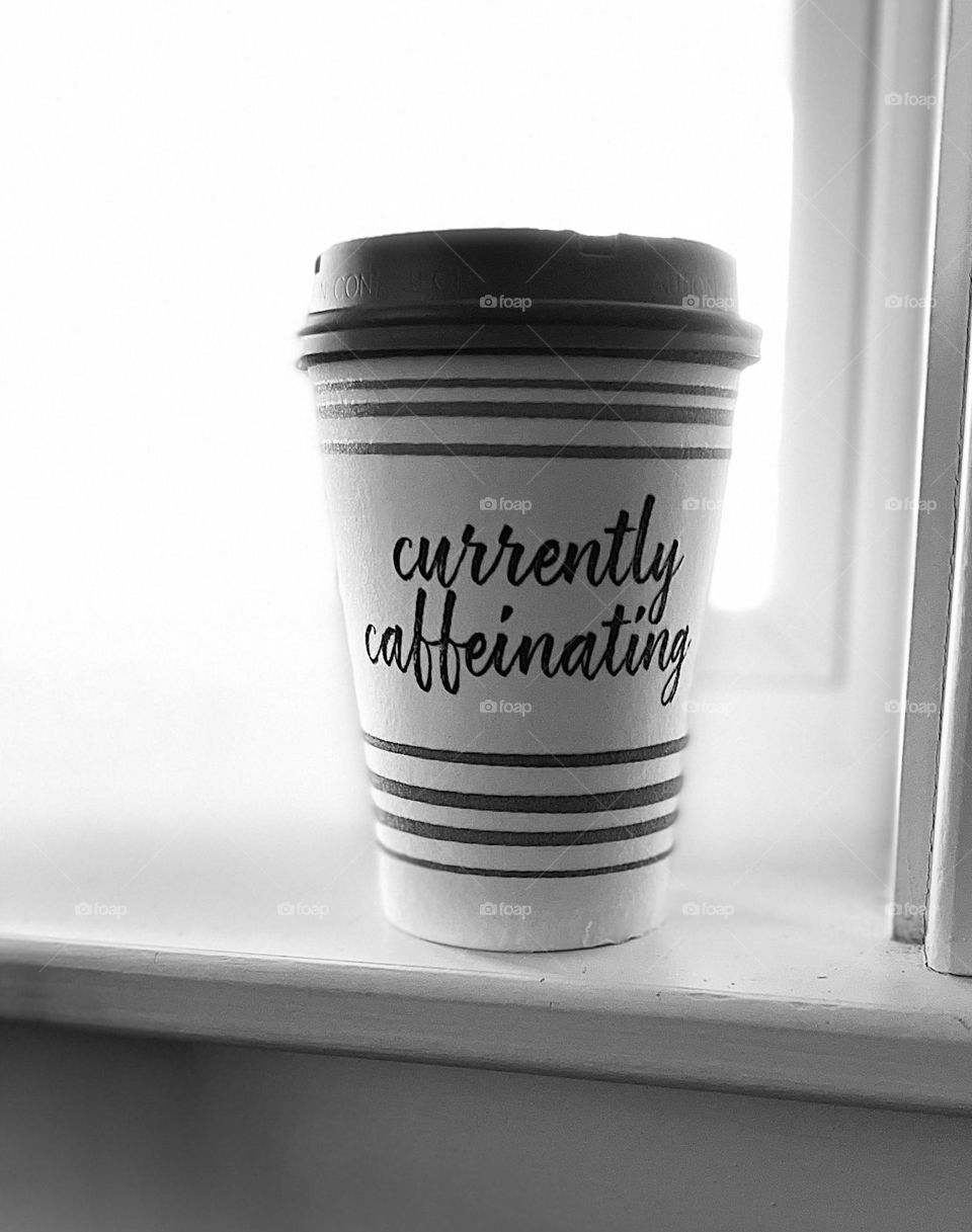 A coffee cup in black and white on a windowsill.