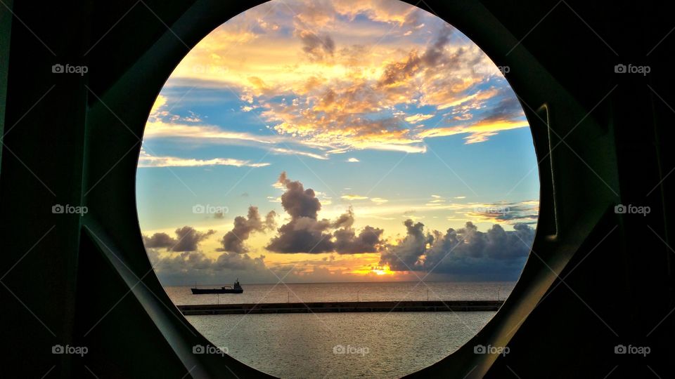view of sunset through port hole of ship.. Barbados