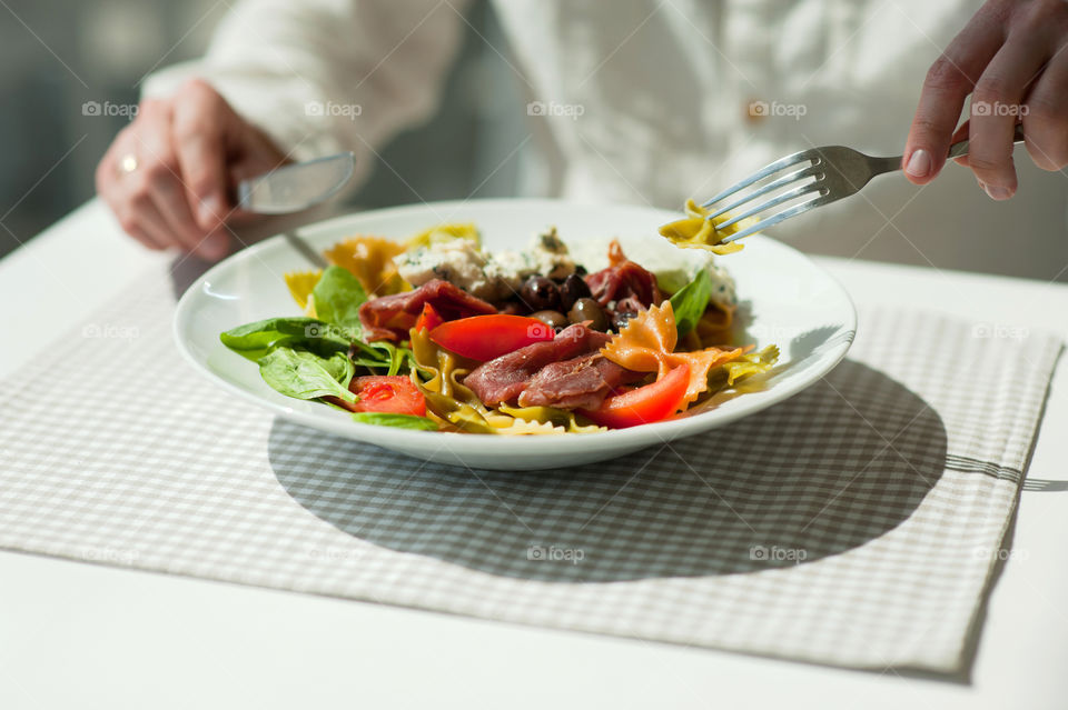 close-up of a young man eating a salad in a light kitchen