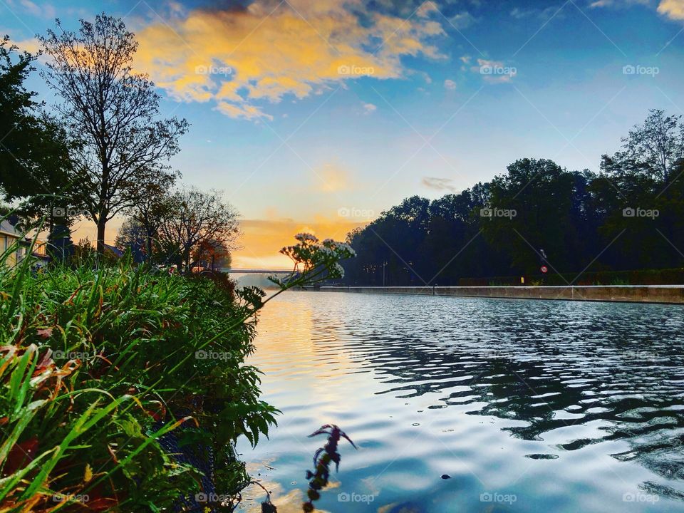 Dawn of the day reflected in the water as seen from the riverside