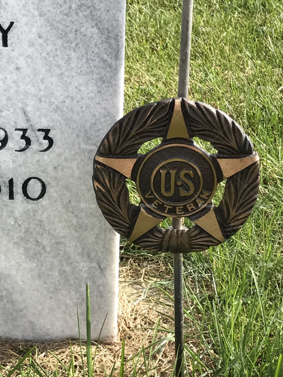 A marker for a U.S. Veteran next to a tombstone.