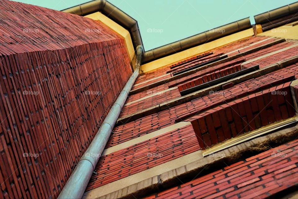 Bottom view of a brick building with a downspout