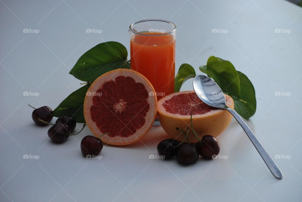 Healthy breakfast with fruit and juice , diet , orange juice, cherries , green leaves, grapefruit , spoon