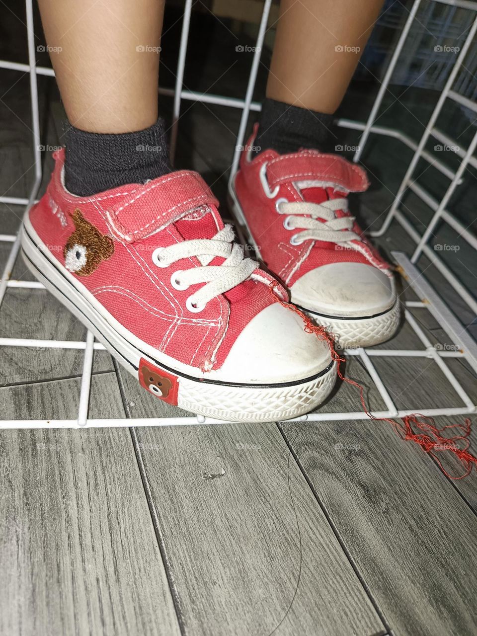 "Little feet in red sneakers, exploring the world one step at a time, with threads unraveling like tiny trails of adventure."