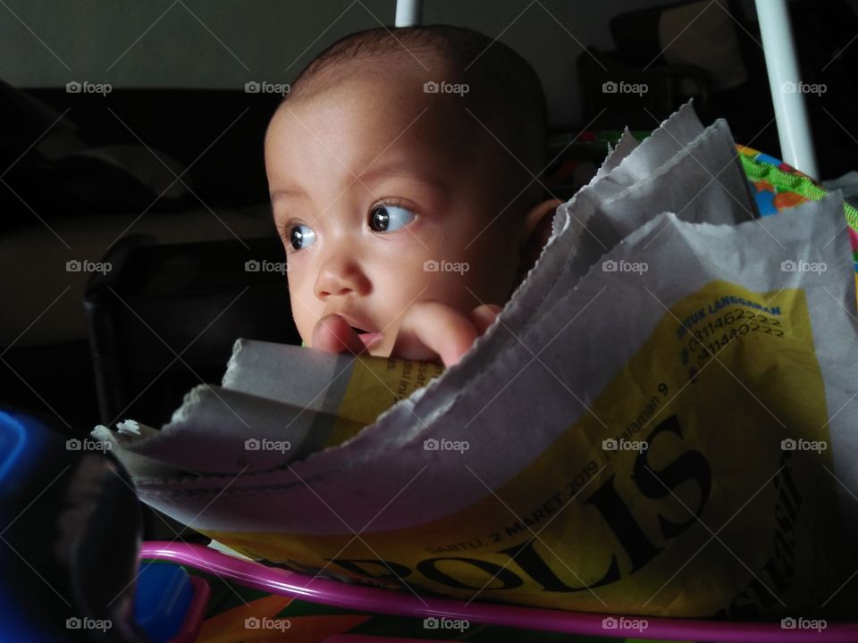 Indonesian baby reading a newspaper