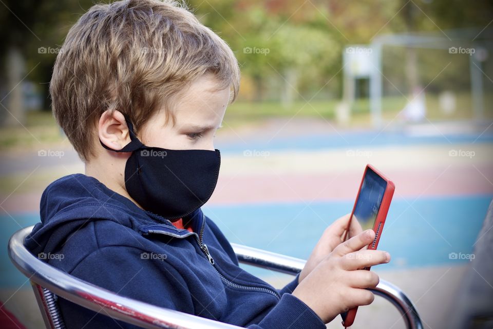 Boy wearing a mask playing on his tablet