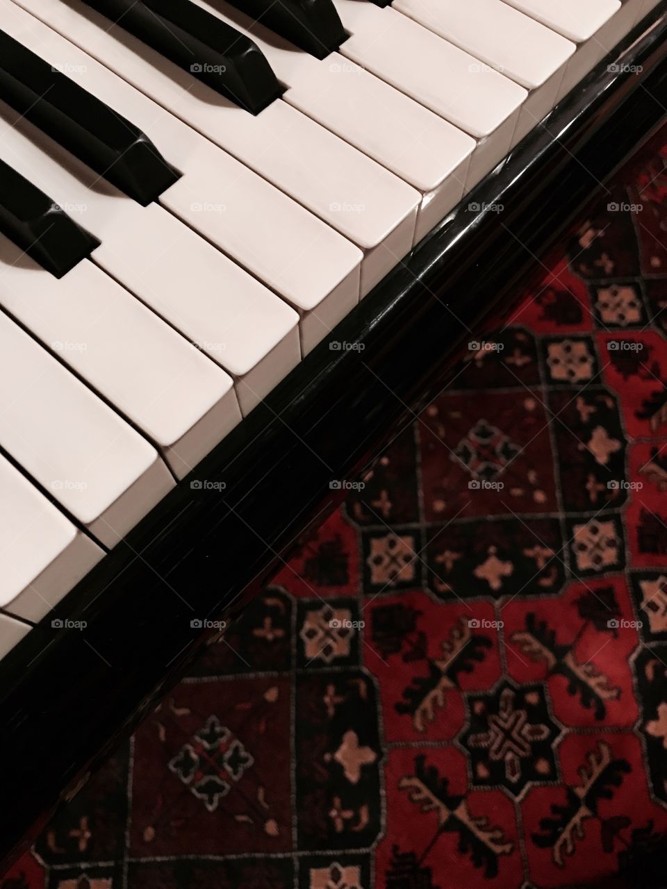 Piano keys over a red Persian rug