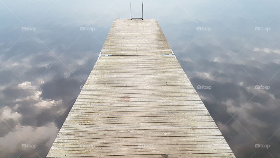 Wooden pier and reflections from the sky and clouds in the water , brygga i trä reflektion himmel 