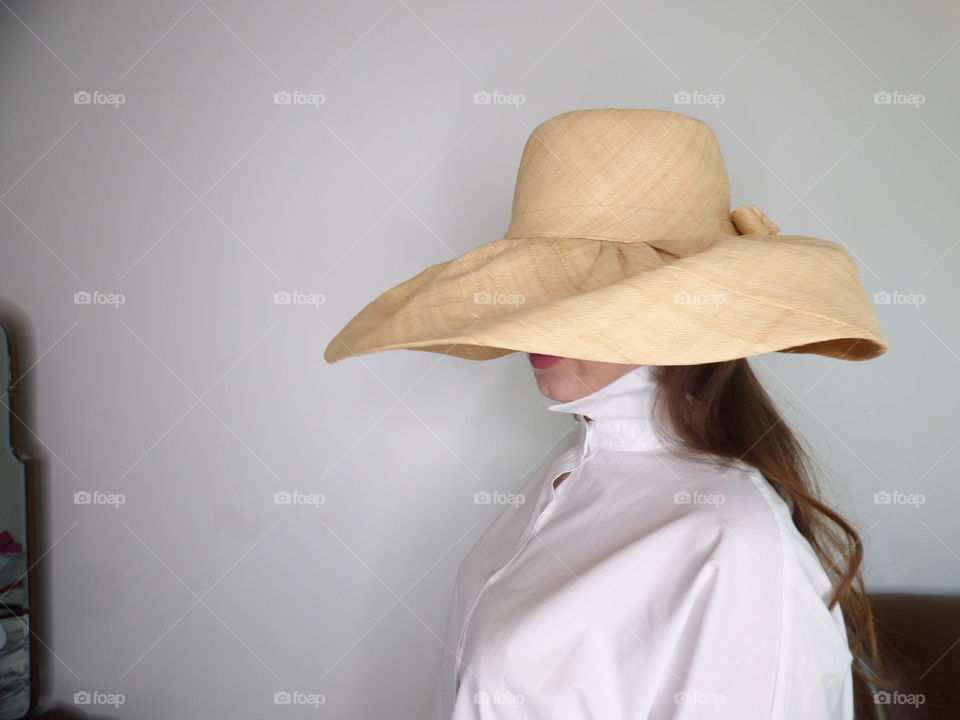 pretty girl wearing a large straw hat and white shirt