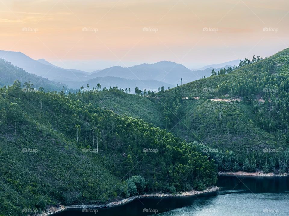 Dusk over tree covered mountains that stretch out in the distance.