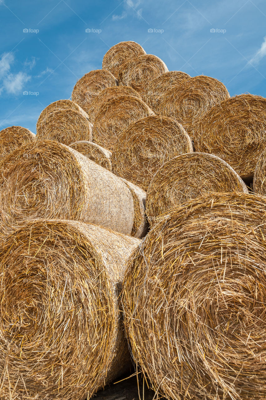 Round hay bales stacked on top of each other forming a piramide shape.