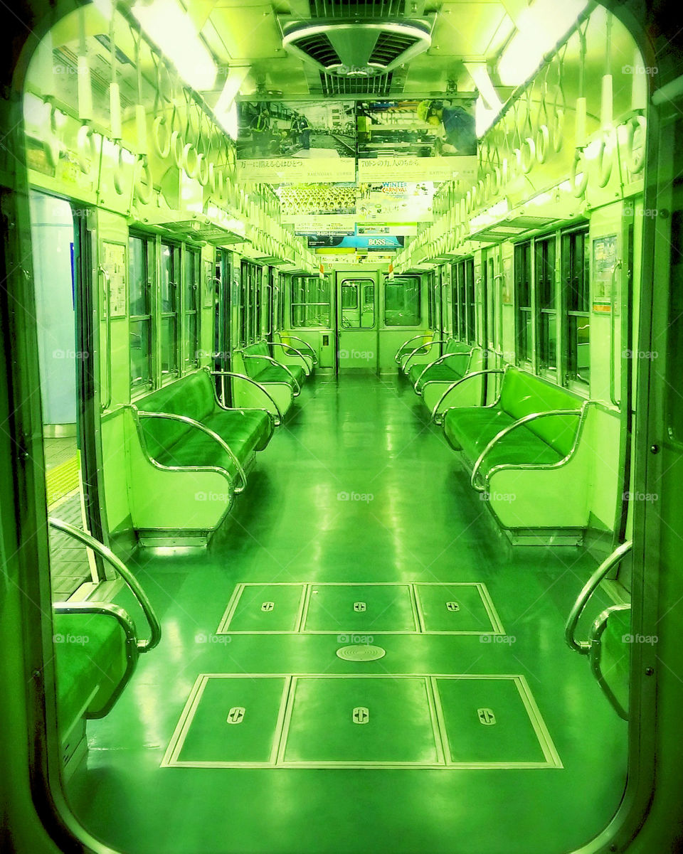 Empty subway train covered in all green from seats to walls.