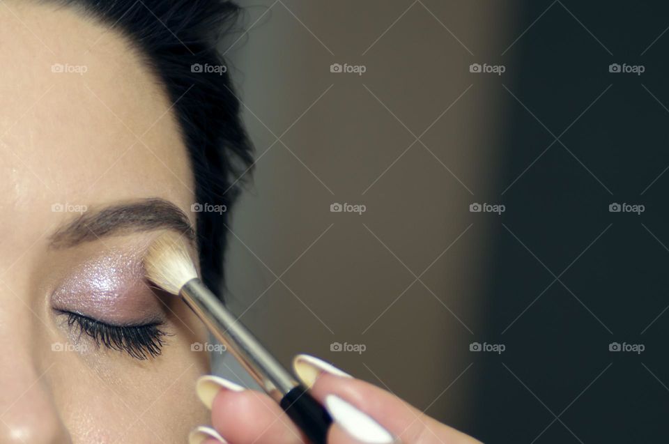 A make-up artist makes makeup for a young woman with long eyelashes and a gentle natural complexion. Beautiful, healthy skin. Well-groomed eyebrows.
