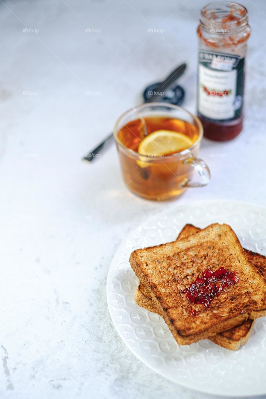 Toast bread with strawberry jem and served with lemon tea for breakfast.