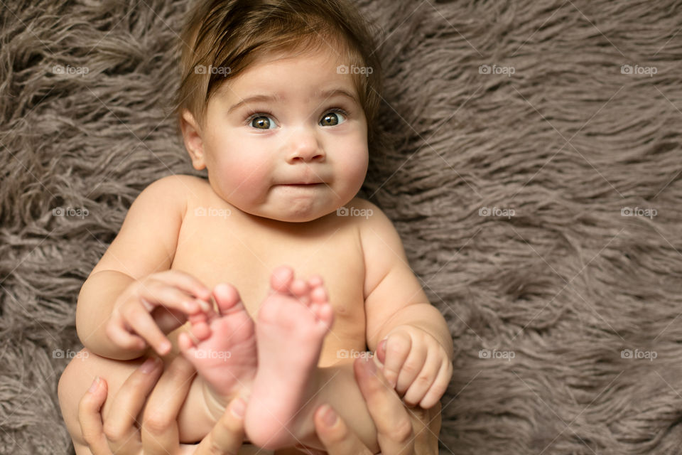 Baby lying on gray soft carpet