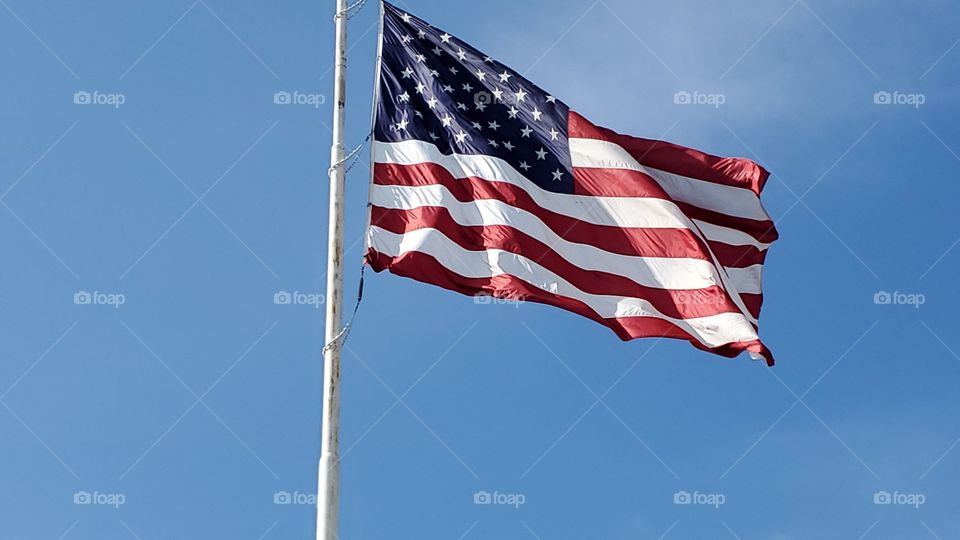 Large United States of America flag with a blue sky background.