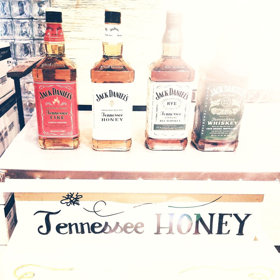 Flavors of Tennessee, best of caramel colored whiskey from Jack Daniel's distillery bottleshop with display feature of multiple label bottles and Tennessee Honey table, truly capturing the essence of vintage summer drinks.