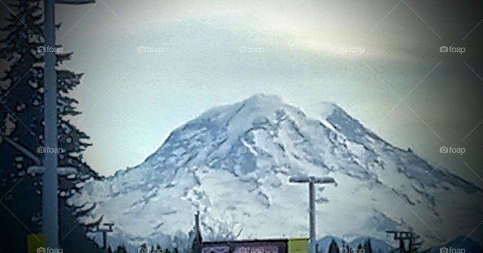 A snow capped, majestic mountain on a cloudy day seen from this small town country store.