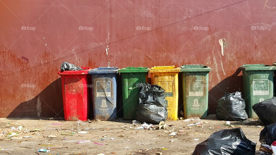 colorful recycle bin. colorful recycle bin, red green blue yellow,  outdoor  dirty plastic container on  Crimson concrete wall background