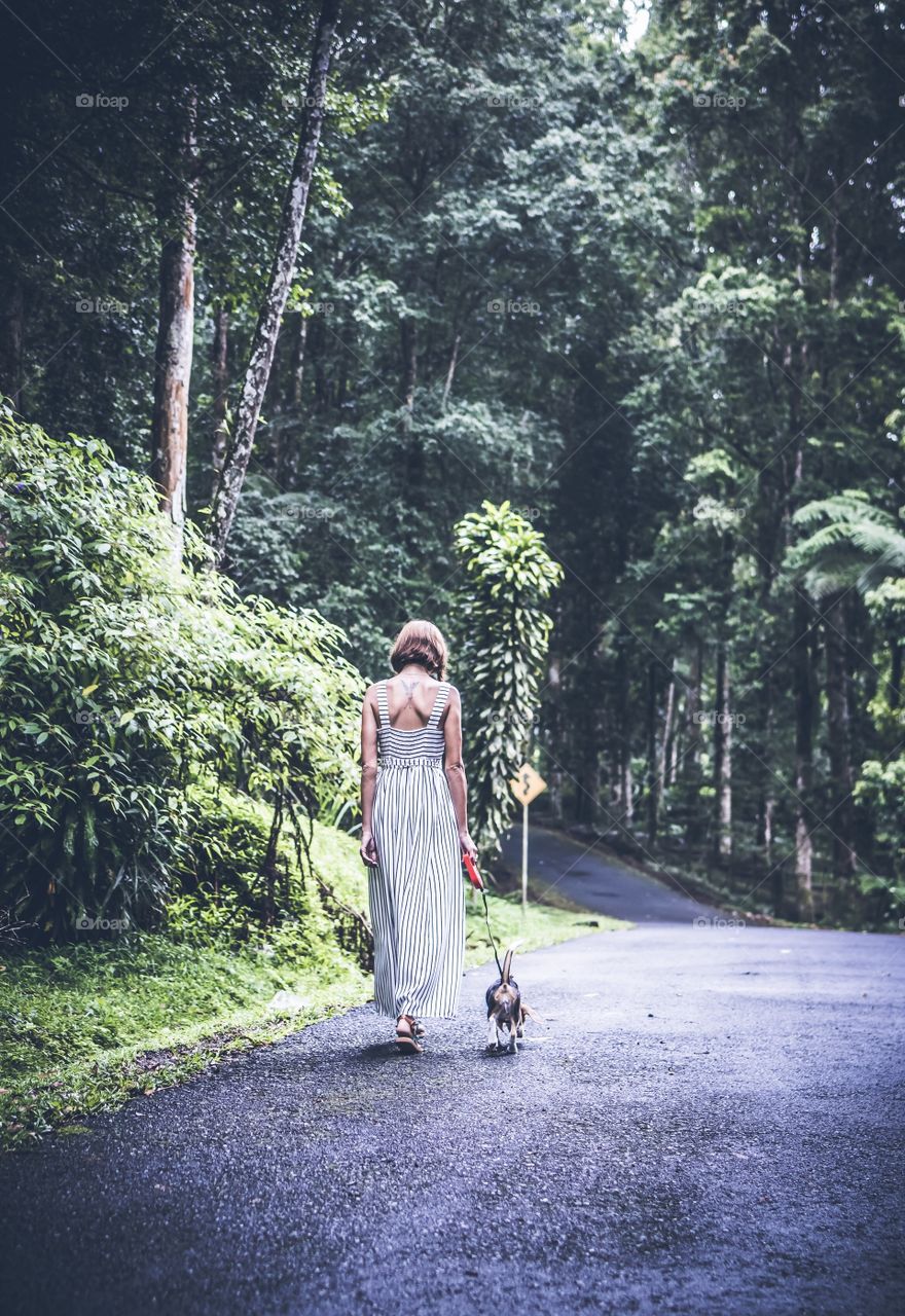 The girl walks with the dog in the botanical garden. Bali island.