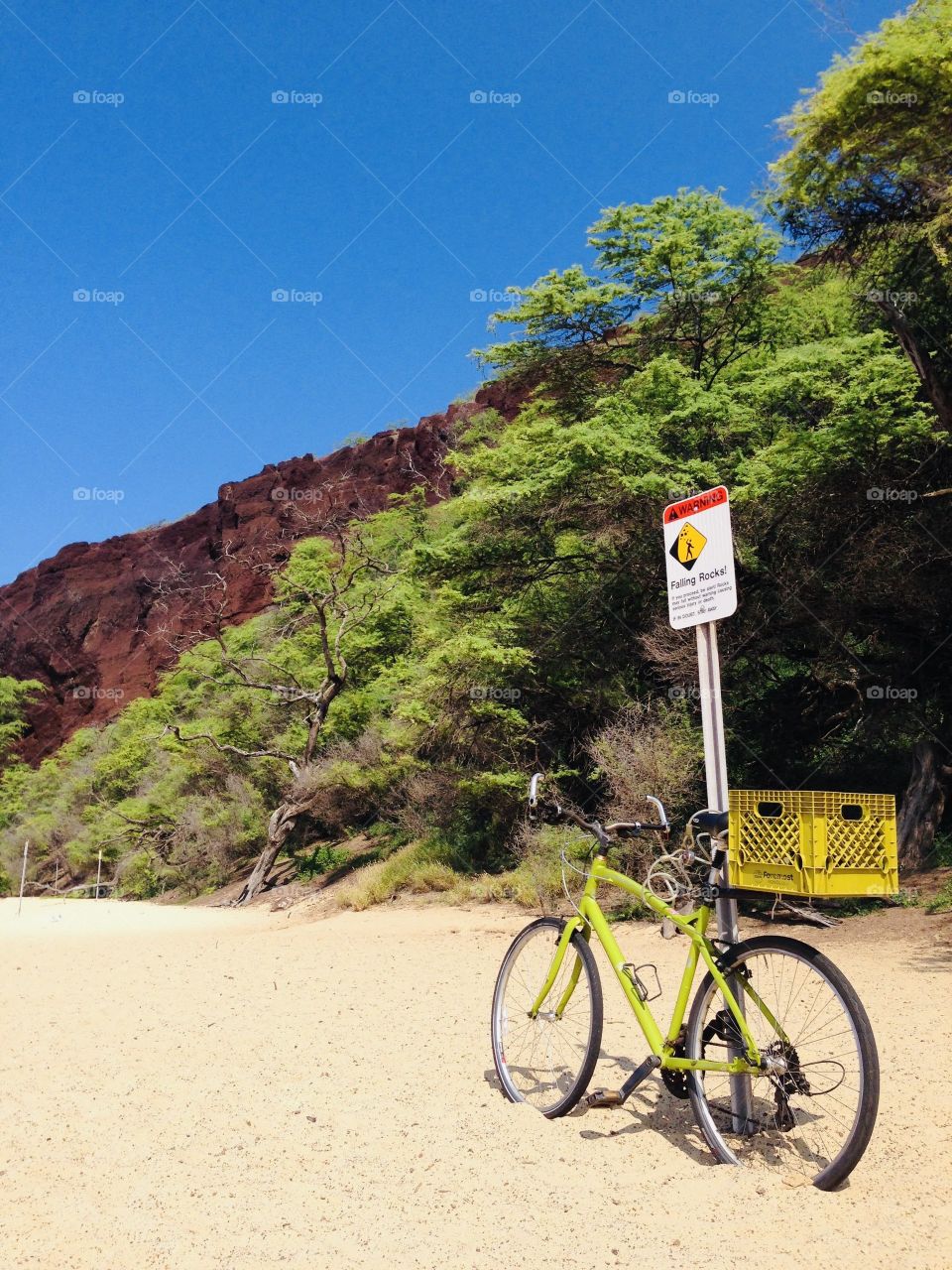 Bicycle leaned up against sign post at beach with rocky Cliff background