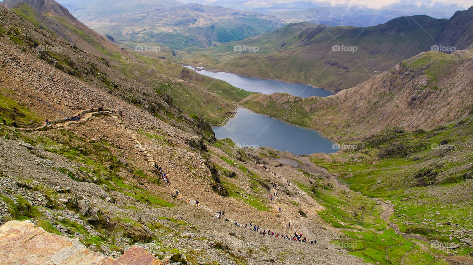 View at valley footpaths leading up to the Snowdon peak. Hikers walking in distance. Snowdonia National Park. Wales. UK.