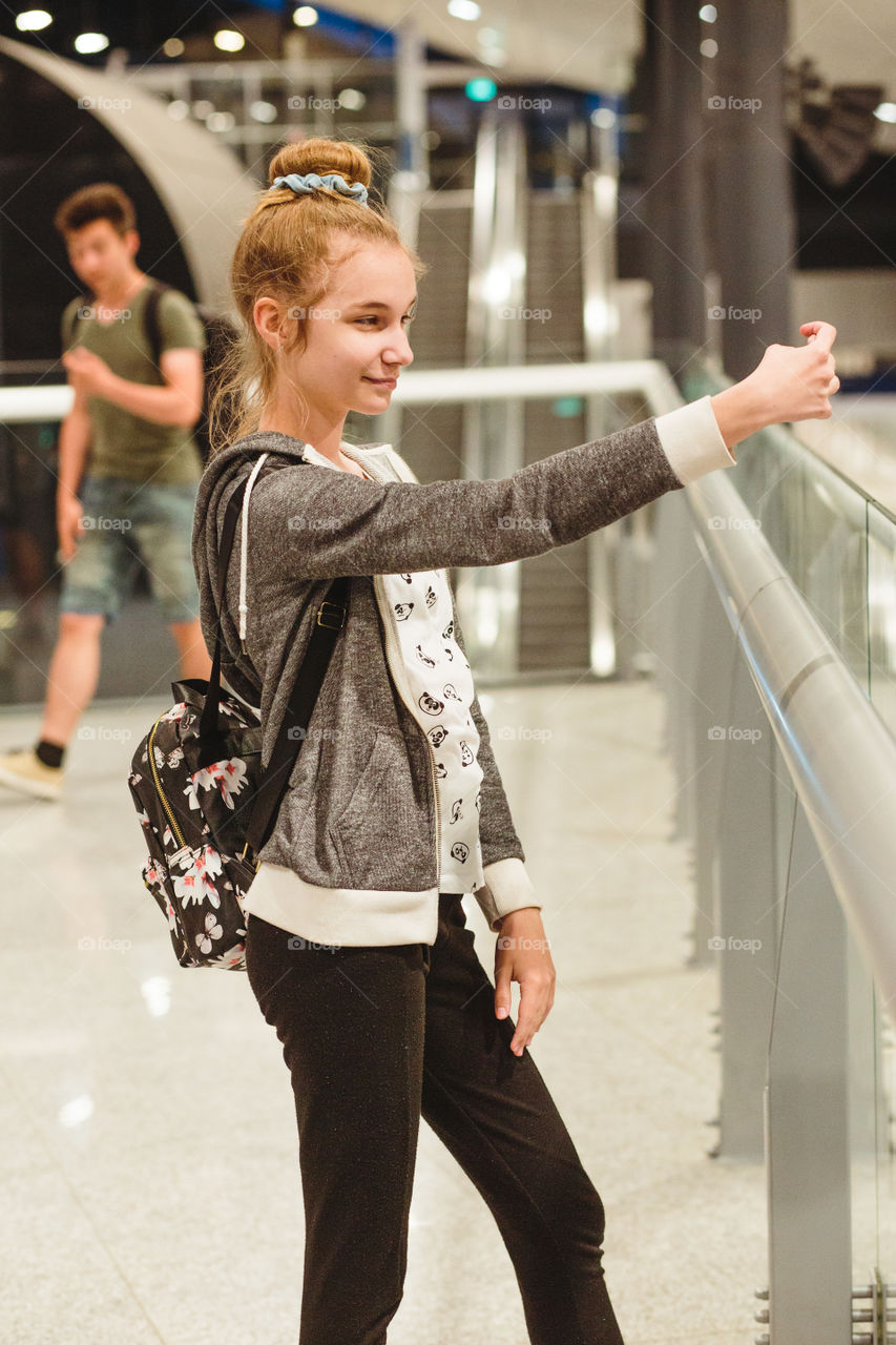 Young woman taking selfie using smartphone standing in railway station