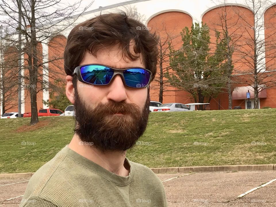 Man with full beard and sunglasses in town outside 